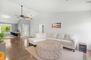 Living area with an office area, wood finished floors, ceiling fan, and high vaulted ceiling