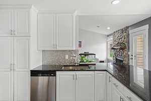 Kitchen with stainless steel dishwasher, white cabinets, tasteful backsplash, and recessed lighting