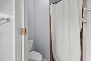 Full bathroom with toilet and a shower with shower curtain