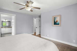 Bedroom with dark wood finished floors, ensuite bathroom, and a ceiling fan