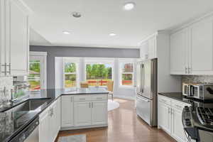 Kitchen featuring appliances with stainless steel finishes, healthy amount of natural light, white cabinets, tasteful backsplash, and recessed lighting