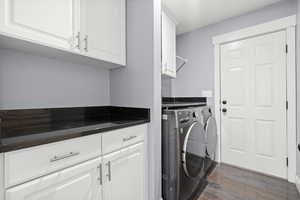 Laundry room featuring independent washer and dryer, dark wood finished floors, and cabinet space