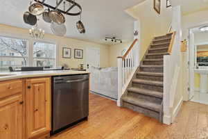 Kitchen featuring light countertops, appliances with stainless steel finishes, a textured ceiling, light wood finished floors, and open floor plan
