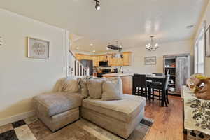 Living room with a chandelier, light wood-type flooring, stairs, a textured ceiling, and recessed lighting
