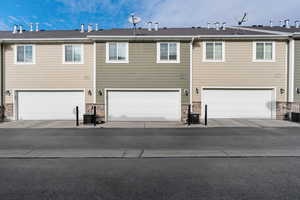 Back of property featuring an attached garage and stone siding