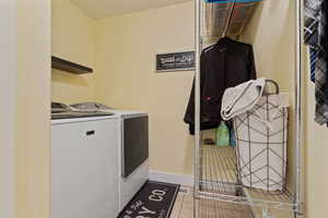 Washroom with washing machine and clothes dryer and light tile patterned floors