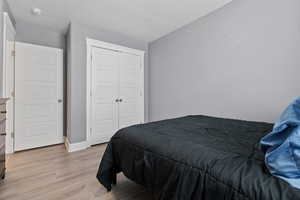 Bedroom featuring light wood-style floors, a closet, and a textured ceiling