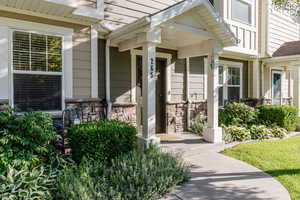 View of exterior entry featuring stone siding and covered porch