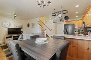 Dining area with stairway, a textured ceiling, light wood finished floors, and a chandelier