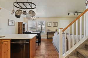 Kitchen featuring dishwasher, light countertops, a textured ceiling, dark wood-style flooring, and a chandelier