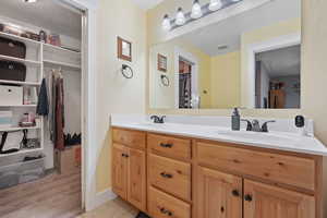 Full bath featuring a walk in closet, double vanity, a textured ceiling, and light wood-type flooring
