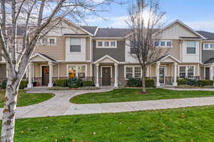 View of front of property with stone siding, a front lawn, board and batten siding, and a residential view