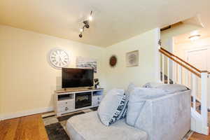 Living area with wood finished floors, stairway, and a textured ceiling