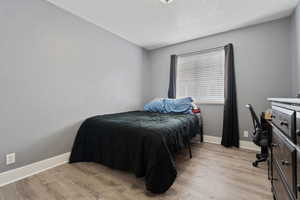 Bedroom with light wood-type flooring, a textured ceiling, and an office area