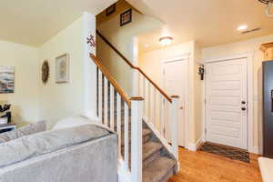 Entrance foyer with light wood-style floors, stairway, and a textured ceiling