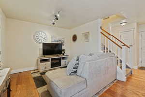 Living area featuring light wood-style floors, stairs, and a textured ceiling