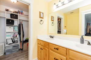 Bathroom featuring wood finished floors, double vanity, and a walk in closet