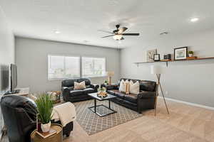 Carpeted living area with a ceiling fan and recessed lighting