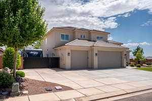 View of front of home with an attached garage, driveway, stucco siding, a tile roof, and a gate