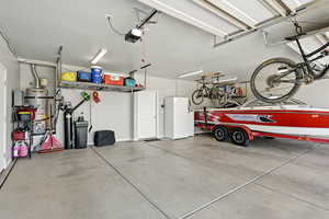 Garage with a garage door opener and strapped water heater
