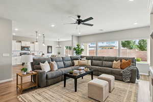 Living room featuring light wood-style flooring, a ceiling fan, recessed lighting, and healthy amount of natural light