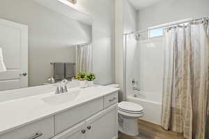 Bathroom with wood finished floors, vanity, and shower / tub combo with curtain