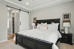 Bedroom with a barn door, light carpet, and recessed lighting
