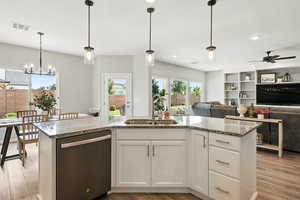 Kitchen with dishwashing machine, open floor plan, light stone counters, light wood-style flooring, and recessed lighting