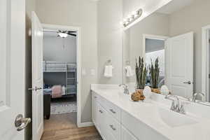 Full bathroom with ensuite bath, wood finished floors, double vanity, and a ceiling fan