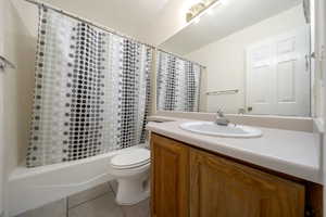 Bathroom with tile patterned floors, vanity, and shower / bathtub combination with curtain