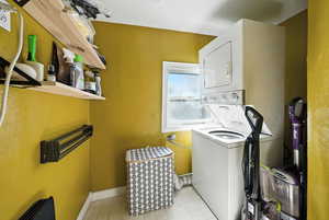 Laundry area with estacked washer and dryer and light tile patterned floors
