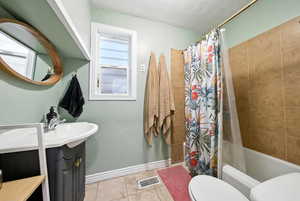 Full bathroom with vanity, tile patterned floors, shower / bath combination with curtain, and a textured ceiling