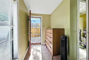 Doorway featuring a textured wall and carpet