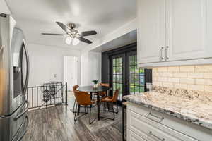 Kitchen featuring stainless steel fridge, decorative backsplash, white cabinets, a ceiling fan, and dark wood-type flooring