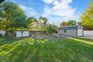 Fenced backyard featuring a vegetable garden and a storage shed