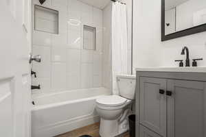 Bathroom with wood finished floors, vanity, and shower / bathtub combination with curtain