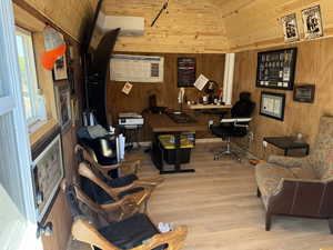 Office featuring wooden walls, vaulted ceiling, wood finished floors, a wall mounted AC, and wood ceiling