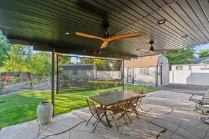 Fenced backyard featuring a vegetable garden, a patio area, a shed, and outdoor dining area