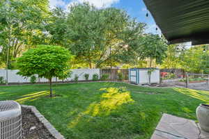 Fenced backyard with a vegetable garden and a storage unit