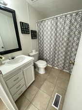 Full bathroom with vanity, tile patterned floors, a textured ceiling, and a shower with shower curtain