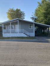 Manufactured / mobile home with a carport, driveway, and covered porch