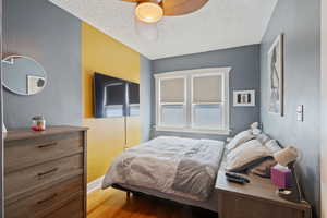 Bedroom featuring wood finished floors, a textured ceiling, and ceiling fan
