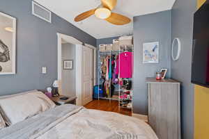 Bedroom with wood finished floors, a closet, a ceiling fan, a textured ceiling, and a spacious closet