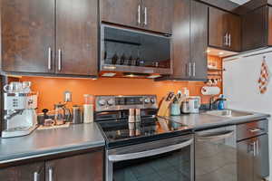 Kitchen featuring appliances with stainless steel finishes, tile patterned floors, and dark brown cabinetry
