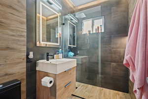 Full bathroom with vanity, walk in shower, and tile walls