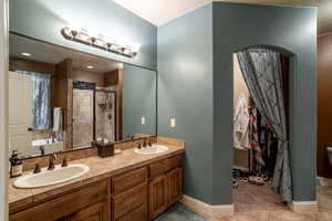 Bathroom featuring a stall shower, double vanity, tile patterned flooring, and a garden tub