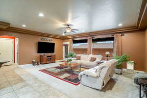 Carpeted living room with arched walkways, a ceiling fan, recessed lighting, and tile patterned flooring
