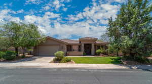 Mediterranean / spanish home featuring a garage, a tiled roof, driveway, stucco siding, and a front lawn
