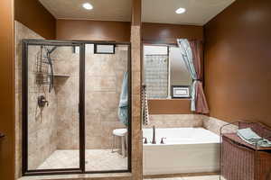 Bathroom with a bath, a stall shower, tile patterned floors, and recessed lighting