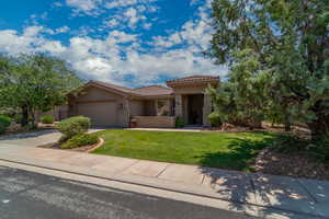 Mediterranean / spanish home with a tile roof, stucco siding, a garage, a front lawn, and concrete driveway